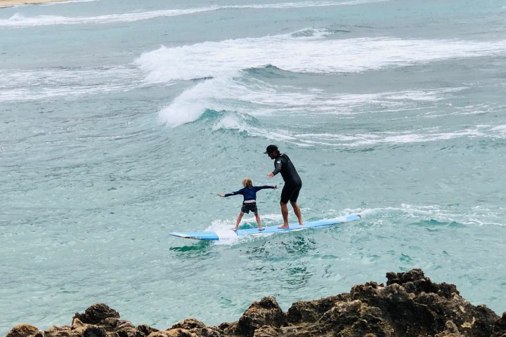 a man riding a wave on top of a beach next to the ocean