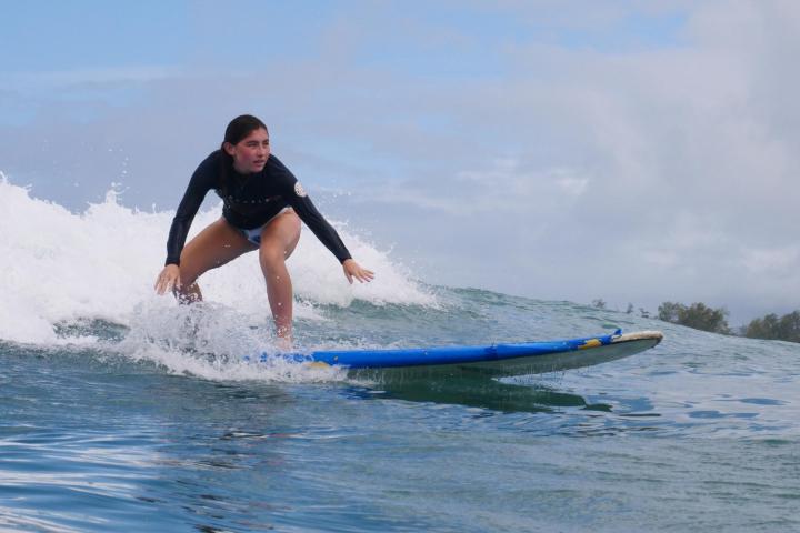a young girl riding a wave on a surfboard in the ocean