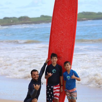 Davis Cleveland standing on a beach holding a surfboard
