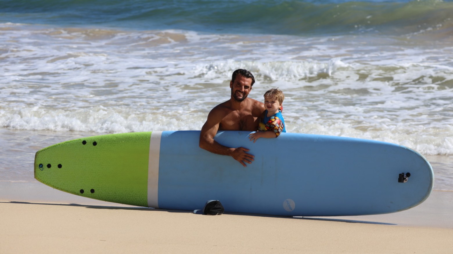 a person sitting on a beach holding a surfboard