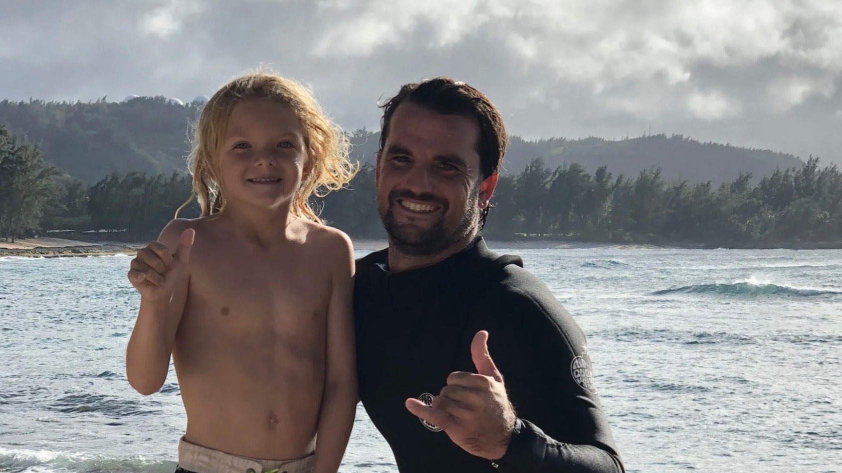 a man standing next to a body of water posing for the camera