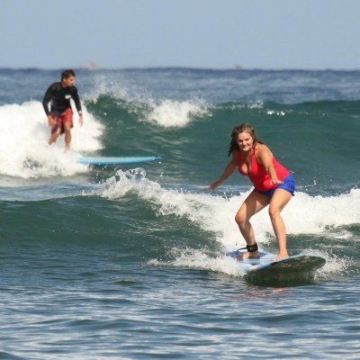 a small girl riding a wave on a surfboard in the ocean