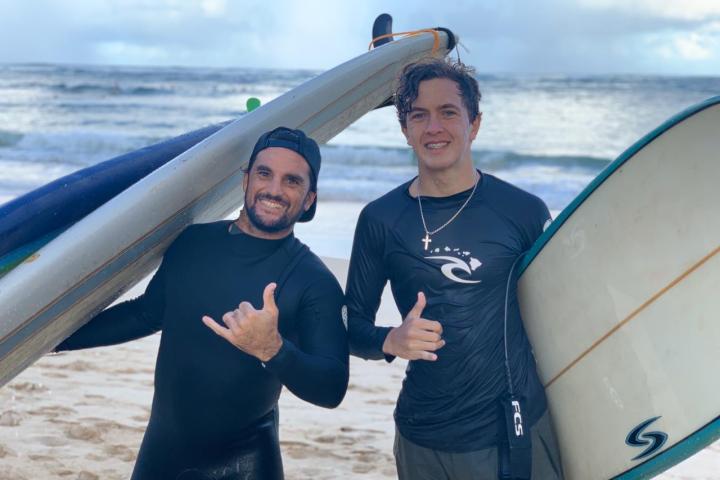 a person wearing a wet suit standing on a beach posing for the camera